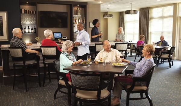 Elegant senior living dining room filled with residents sharing laughter and delicious meals together.