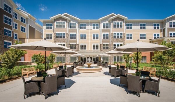 Exterior shot of an Erickson Senior living community building courtyard and patio on a sunny day.
